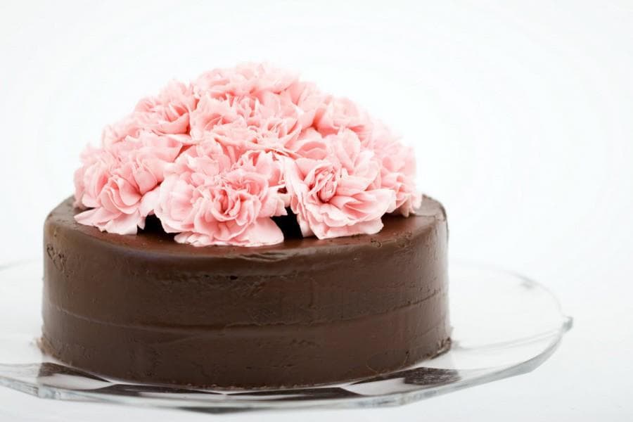 Tort de ciocolată decorat cu flori roz din cremă