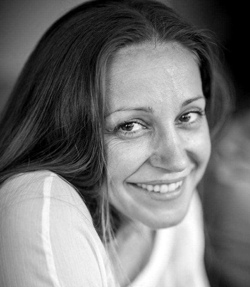 Portret alb-negru al unei femei cu părul lung, zâmbind