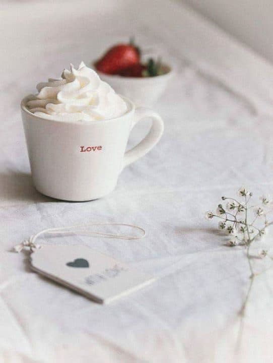 Cană cu frișcă și textul „Love”, pe o pânză albă