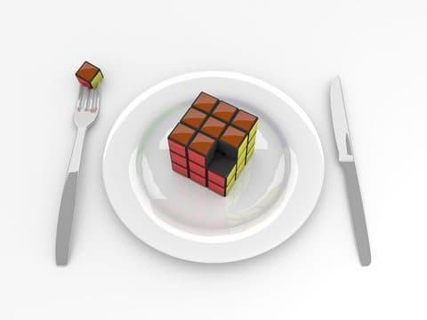 Cub Rubik pe o farfurie, între furculiță și cuțit
