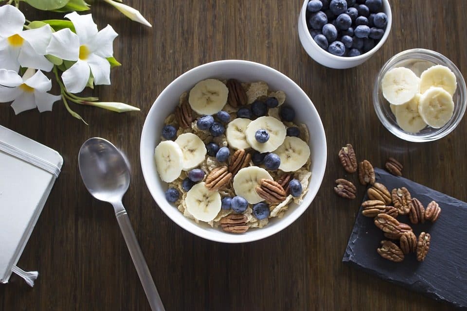 Bol cu cereale, felii de banană, afine și nuci pecan
