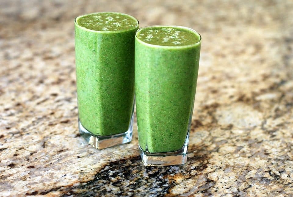 Două pahare cu smoothie verde pe un blat de granit