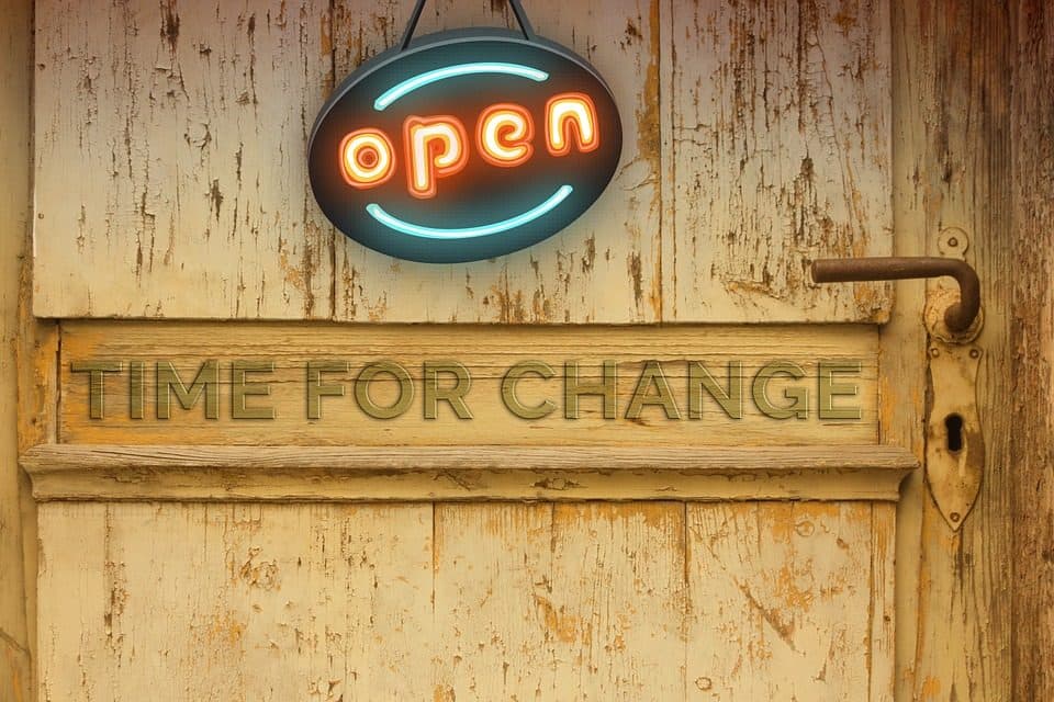 Ușă veche de lemn cu firmă luminoasă „open” și inscripția „TIME FOR CHANGE”