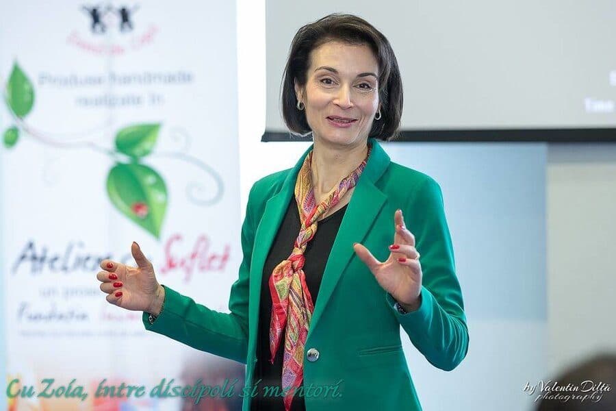 Femeie în sacou verde gesticulând în timp ce susține o prezentare