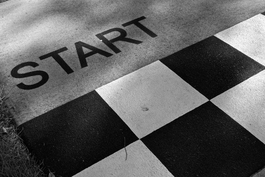 Inscripția „START” pe asfalt, lângă un model în carouri alb-negru