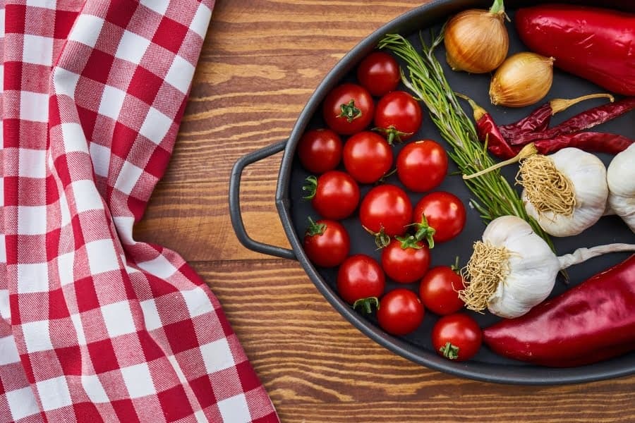 Roșii cherry, ceapă, usturoi și ardei iuți într-o tavă neagră
