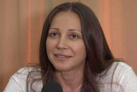 Portret al unei femei brunete zâmbind, cu un microfon în prim-plan