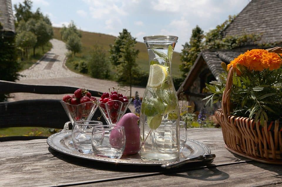 Carafă cu apă, lămâie și mentă pe o masă de lemn, la țară