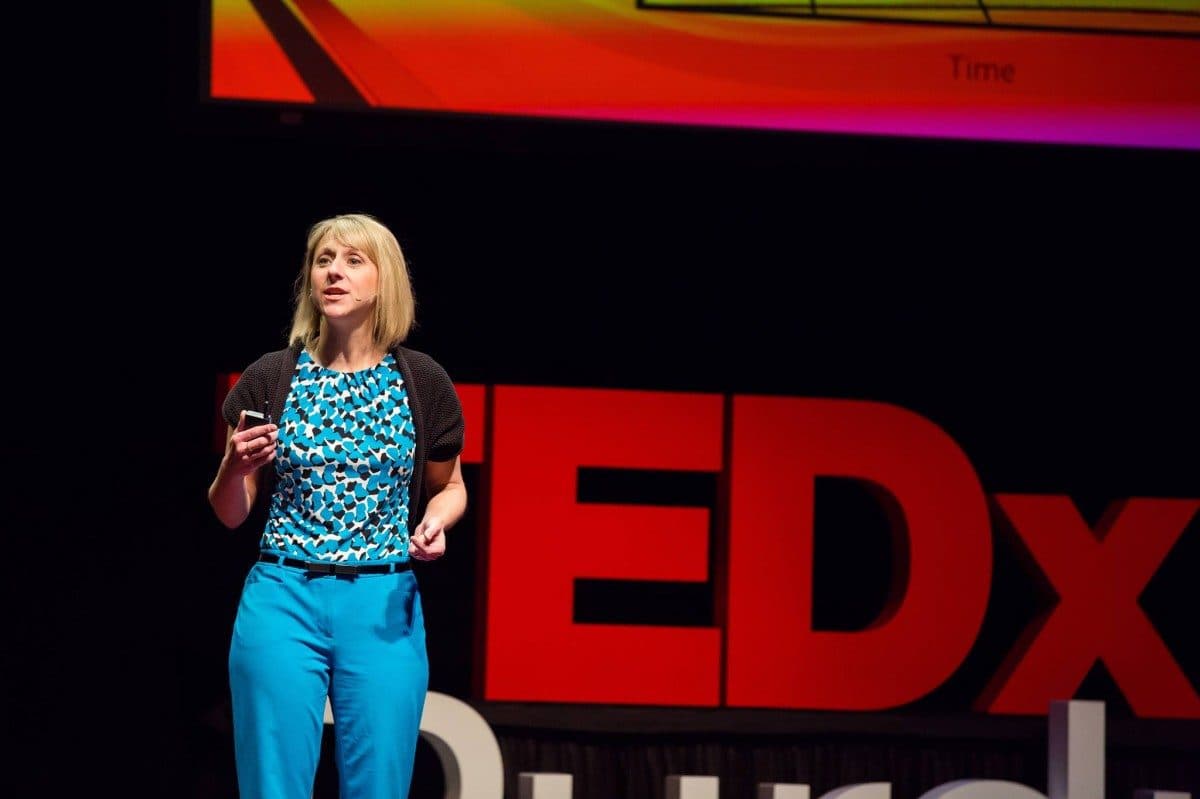 Femeie vorbind pe scenă în fața siglei „TEDx”