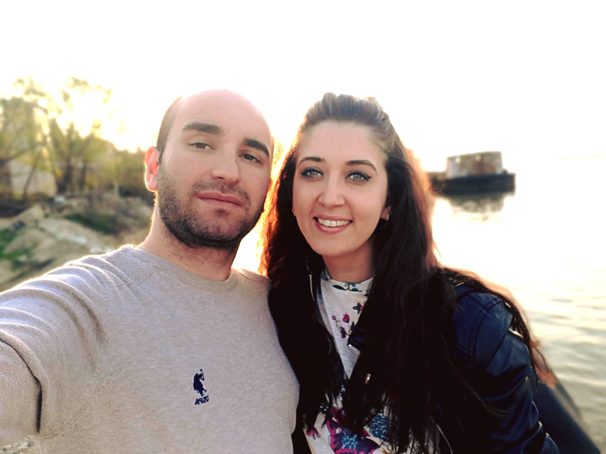 Selfie al unui bărbat și al unei femei lângă apă, la apus