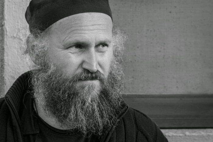 Portret alb-negru al unui bărbat cu barbă lungă și potcap negru