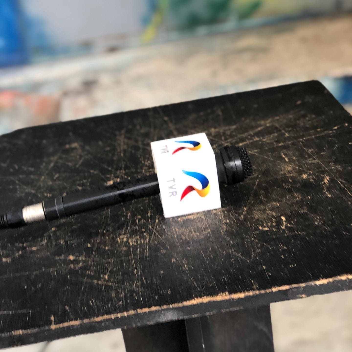 Microfon cu cub inscripționat „TVR”, așezat pe un scaun negru