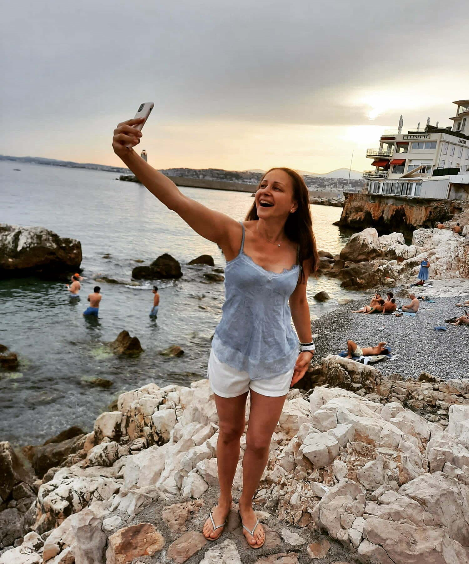 Femeie care își face un selfie pe stânci, la malul mării