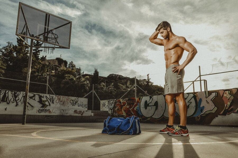 Bărbat pe un teren de baschet, lângă o geantă sport
