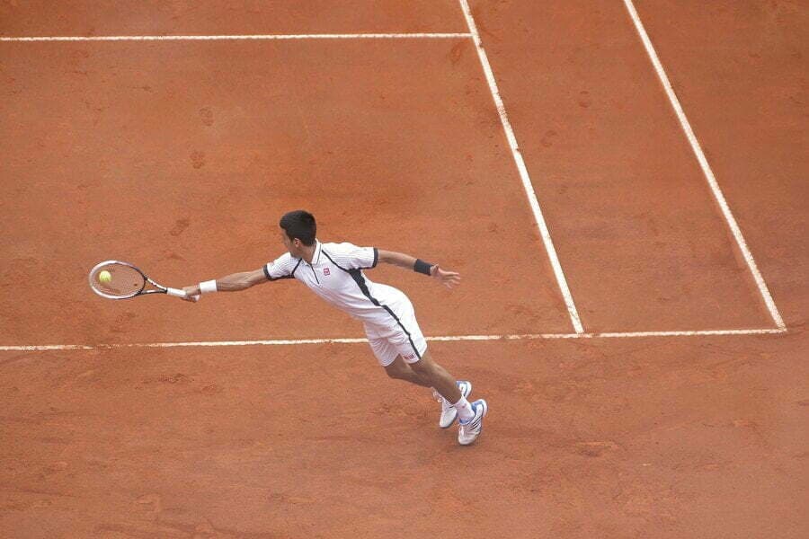 Jucător de tenis întins după minge pe teren de zgură
