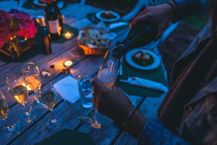 Mâini turnând vin într-un pahar, la o masă cu lumânări