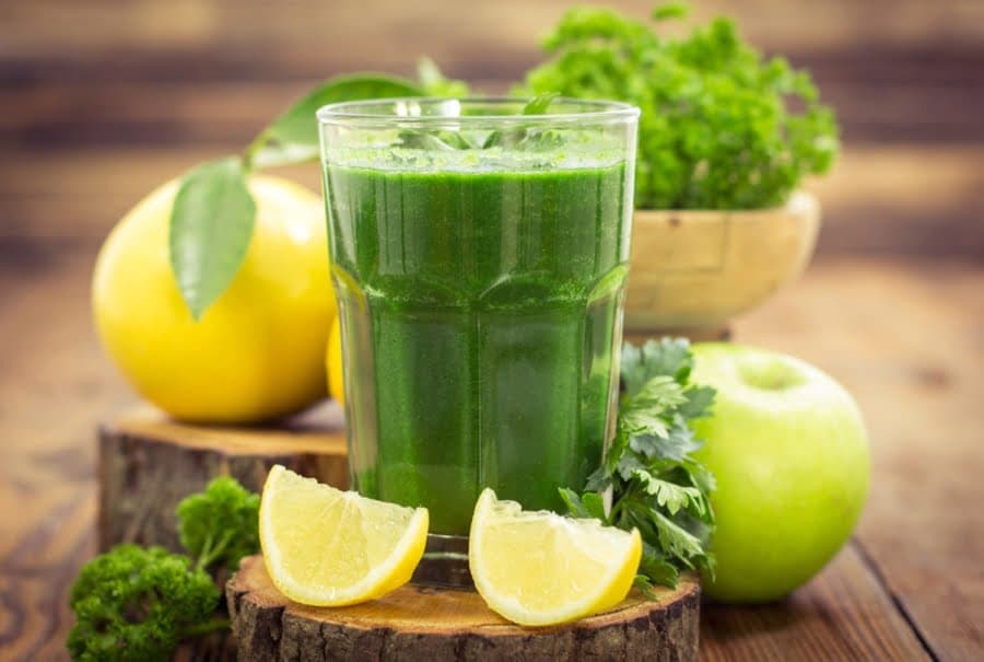 Pahar cu suc verde, lângă lămâie, măr și pătrunjel