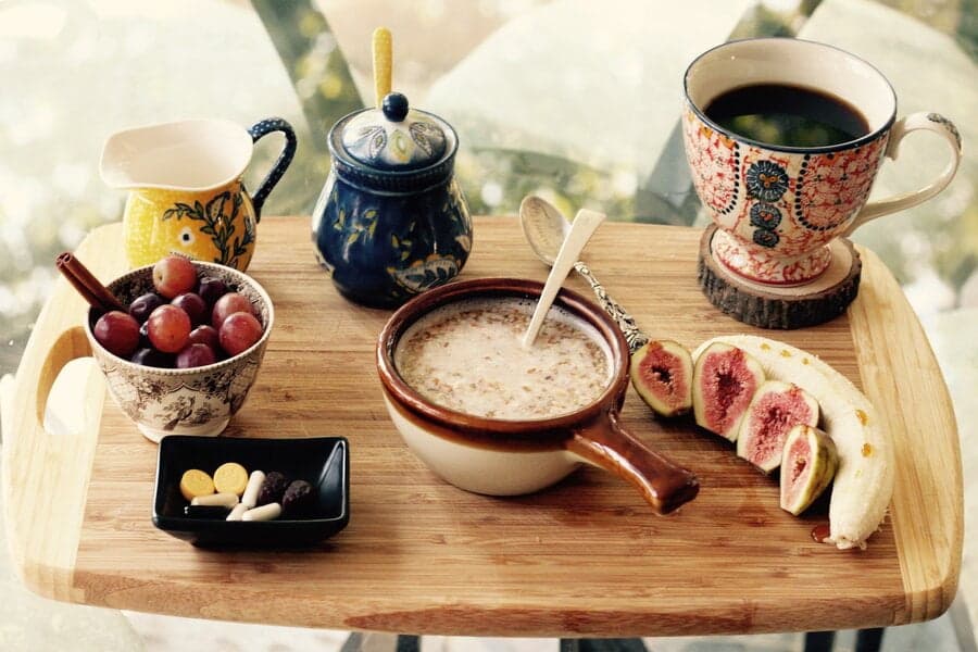 Tavă de lemn cu terci, cafea, struguri, smochine și banană