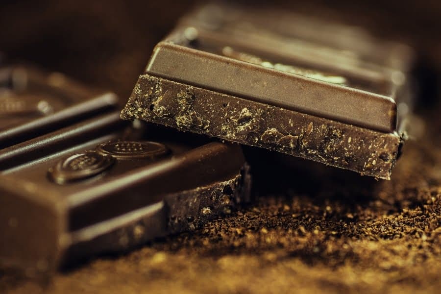 Bucăți de ciocolată neagră pe un blat presărat cu cacao