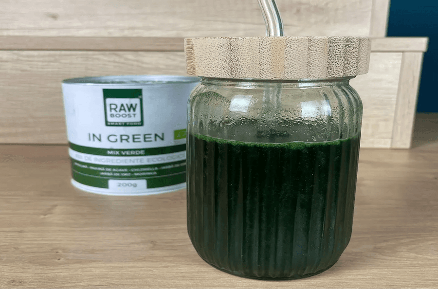 Pahar cu băutură verde și paie, lângă o cutie „Raw Boost In Green”