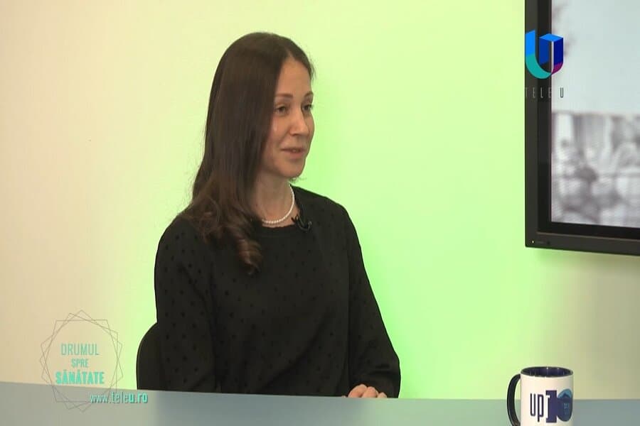 Femeie intervievată în studio TV, cu logoul „Drumul spre sănătate”