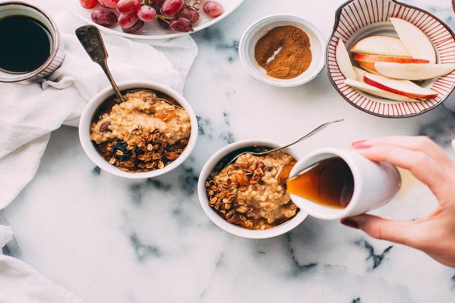 Două boluri cu ovăz și granola, cu sirop turnat deasupra